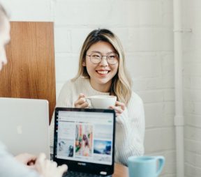 young woman drinking coffee, working at computer