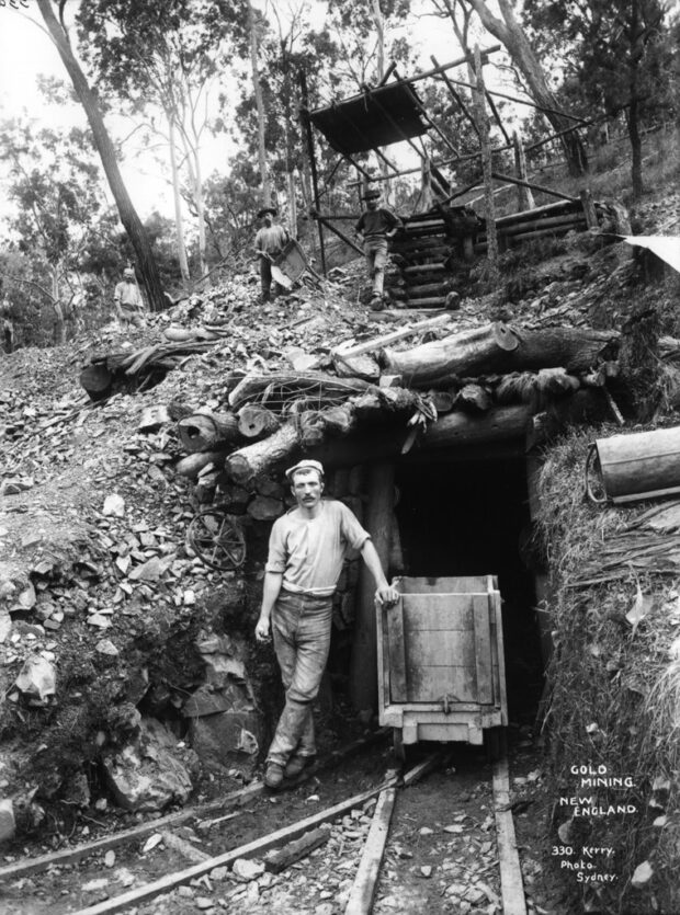 historical black-and-white image of man standing in front of a New England gold mine