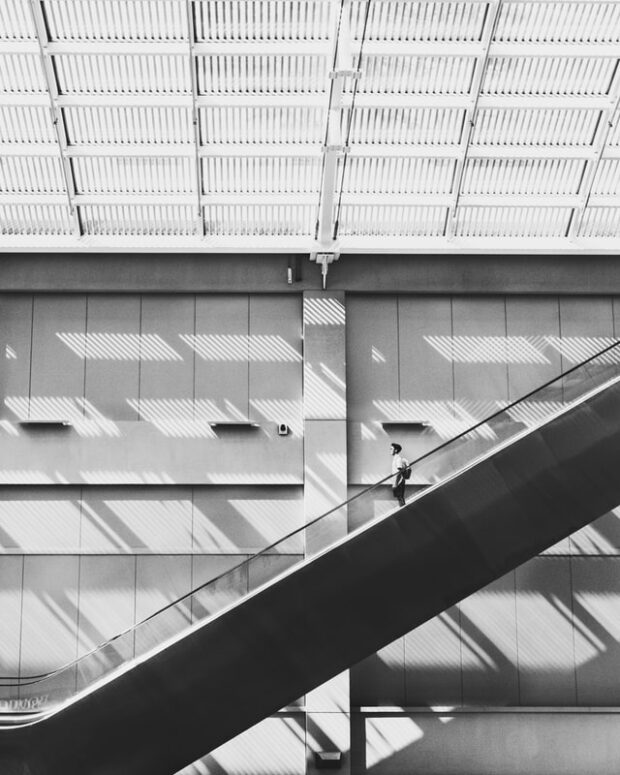 person descending an elevator in black and white