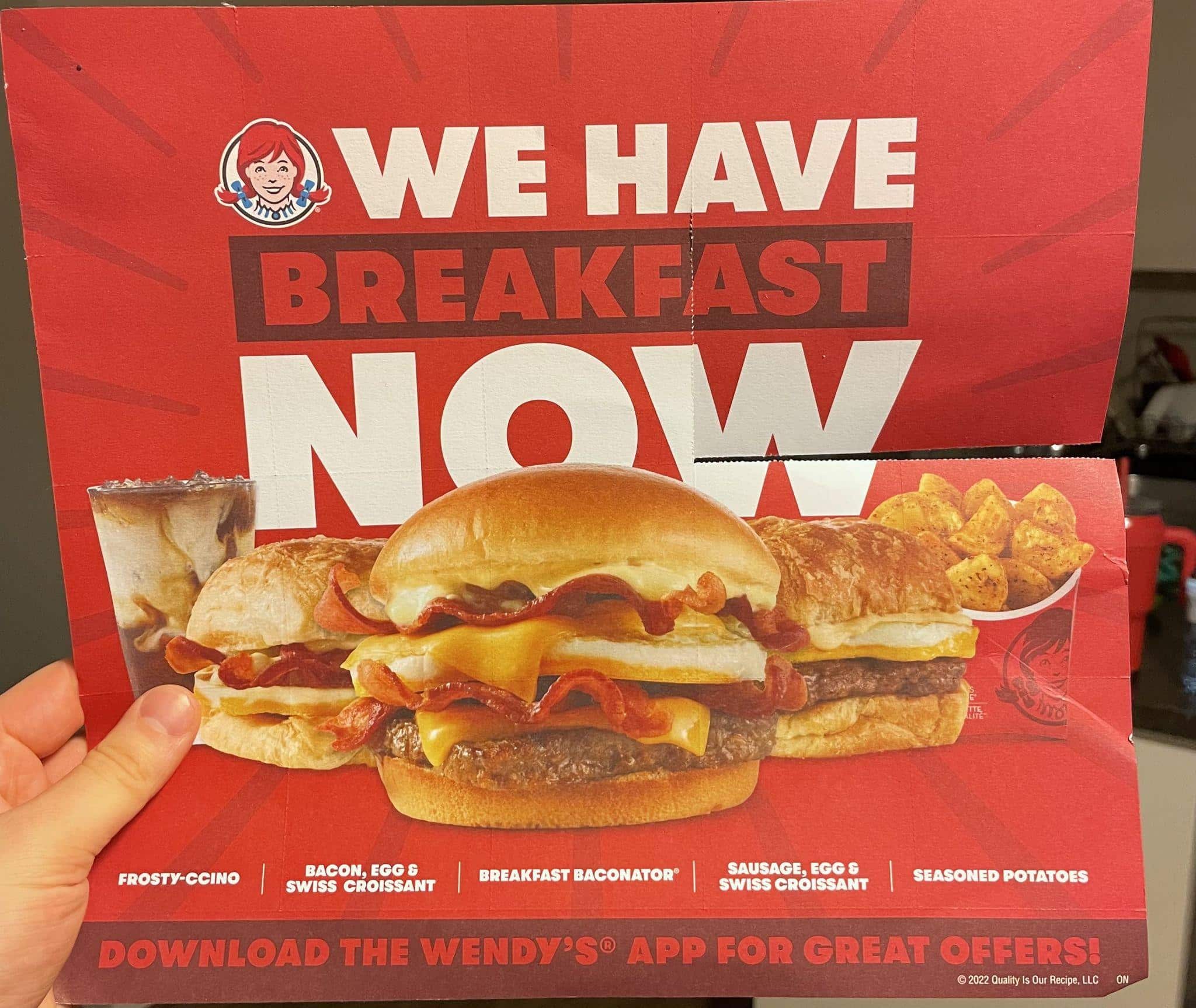 Un volantino della catena di fast food Wendy's che mostra diverse scelte per la colazione. Il testo dice “we have breakfast now” (“facciamo colazione adesso").