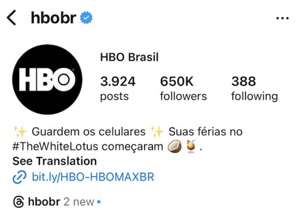 A imagem mostra o perfil da HBO no Brasil, cuja biografia contém a frase “Guardem os celulares. Suas férias no #TheWhileLotus começaram” com emojis de brilho, coco e taça de drinks e um link.