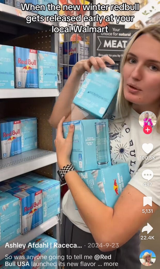 A woman enthusiastically holds multiple boxes of winter edition Red Bull cans at Walmart. Text reads: “When the new winter redbull gets released early at your local Walmart.”