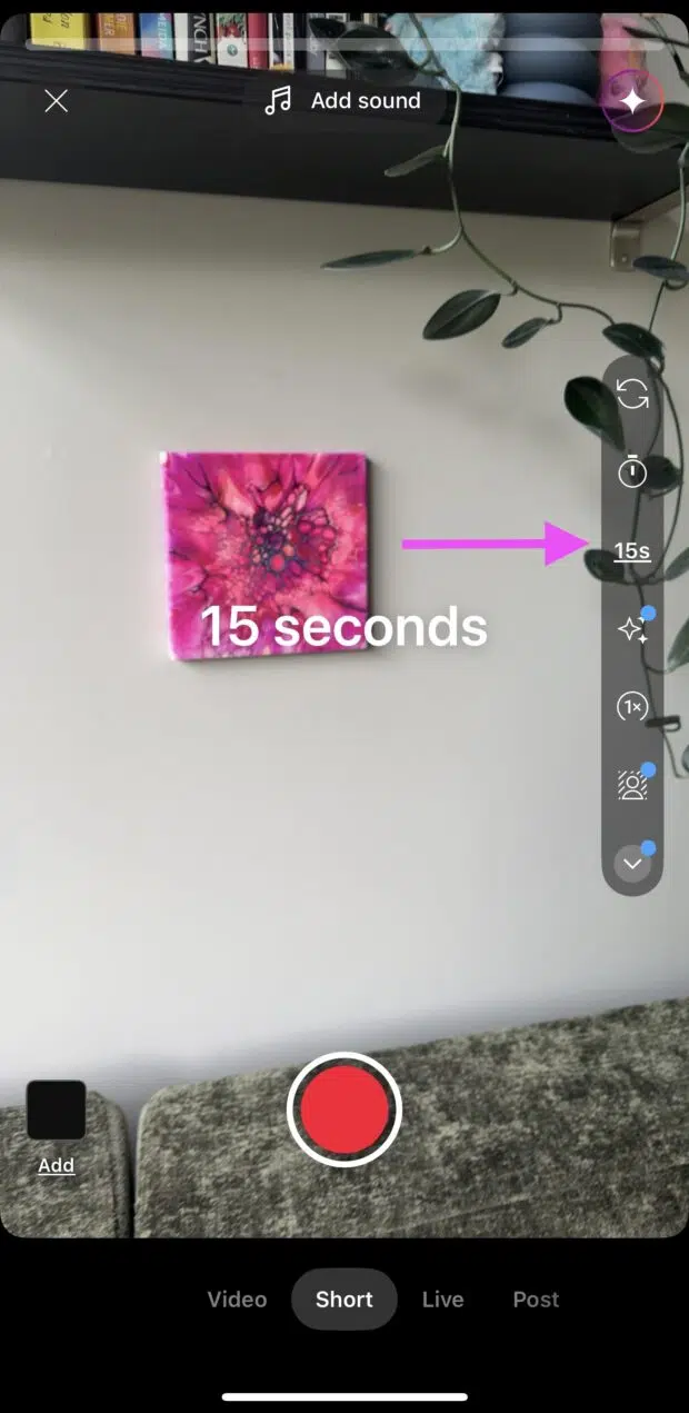 YouTube Shorts screen showing a 15-second duration setting with a pink arrow pointing to the "15s" icon A pink abstract painting is centered on the wall above a gray couch