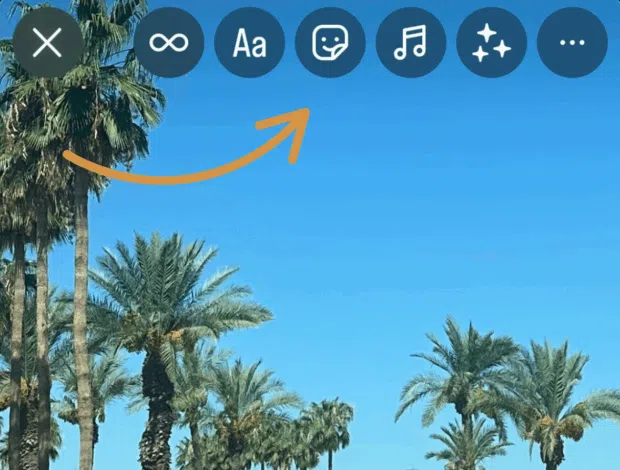 A phone screen displaying an Instagram Story with various editing icons at the top, including infinity symbol, text, sticker, music, and effects, over a clear blue sky with palm trees.