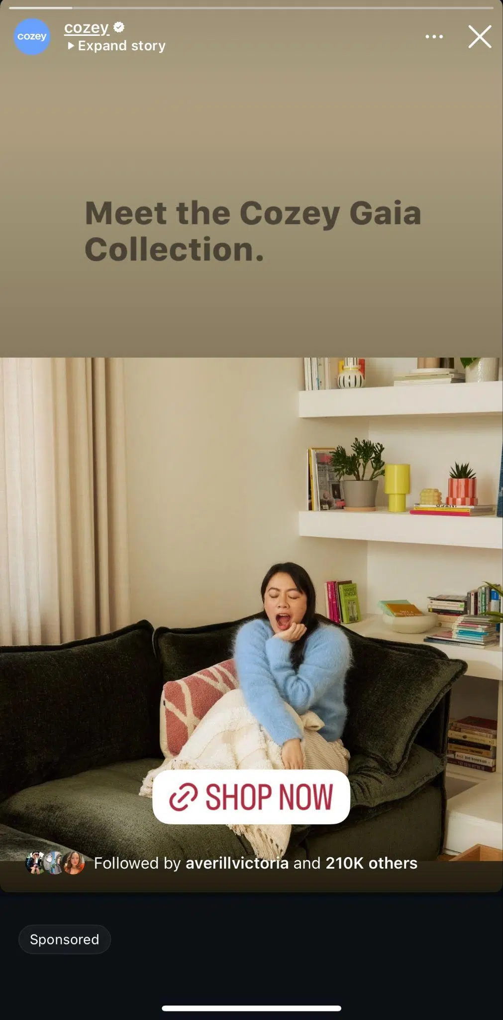 instagram story from cozey that shows a women sitting on a couch yawning with a large shop now instagram sticker overtop